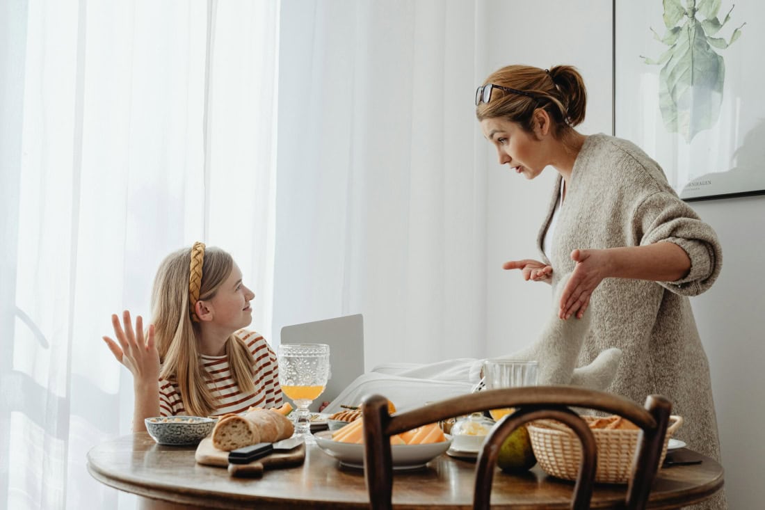 Family at table with mother and daughter over breakfast, homely atmosphere, youth support.